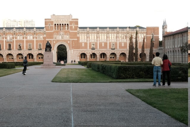 a group of people standing in front of a building Rice University